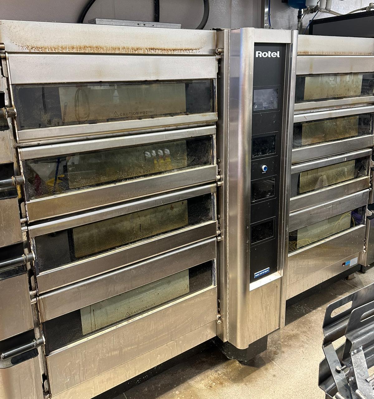 A stack of commercial ovens with grimy doors.