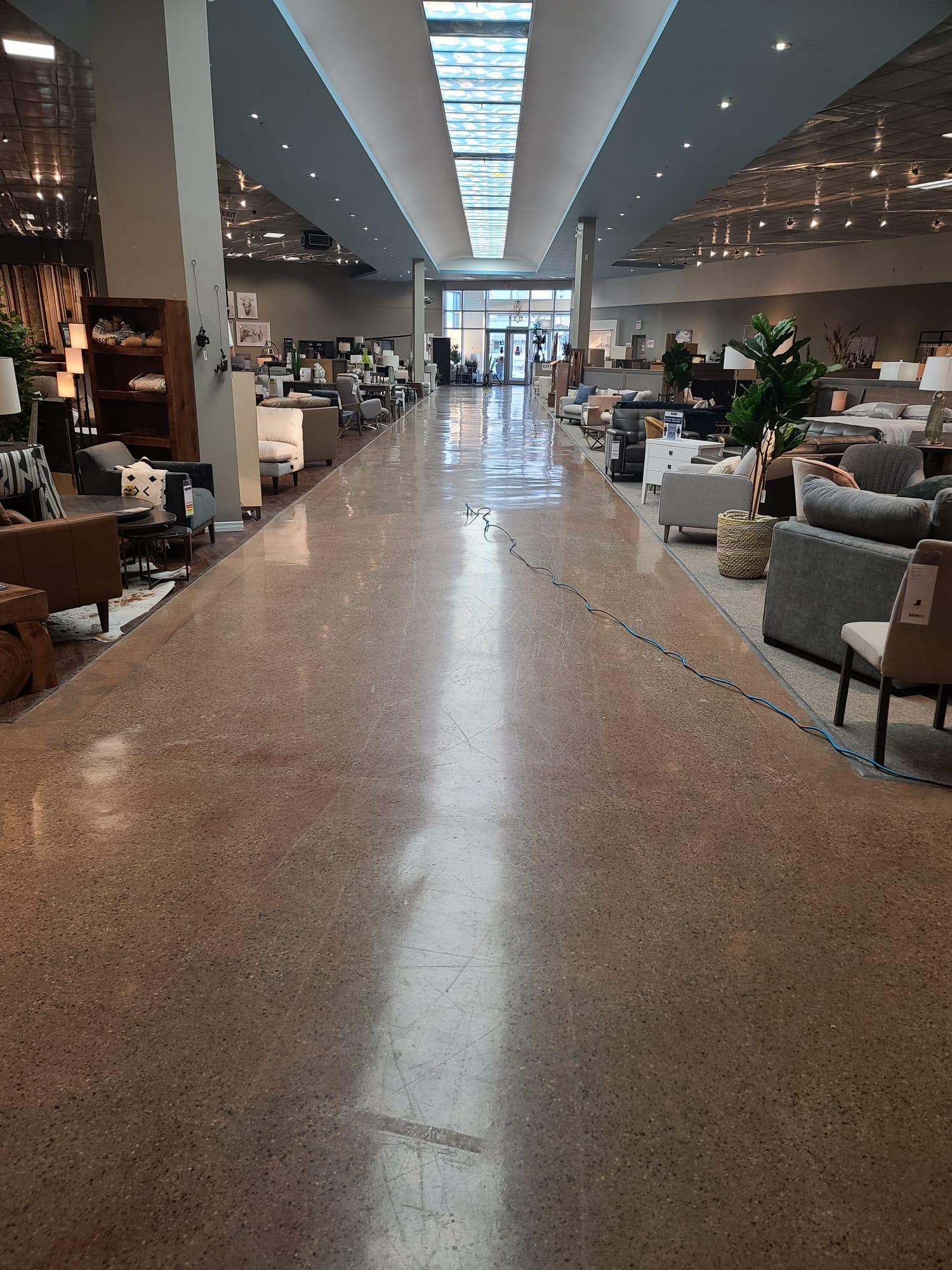 A long showroom floor, dull and streaked, between rows of furniture.